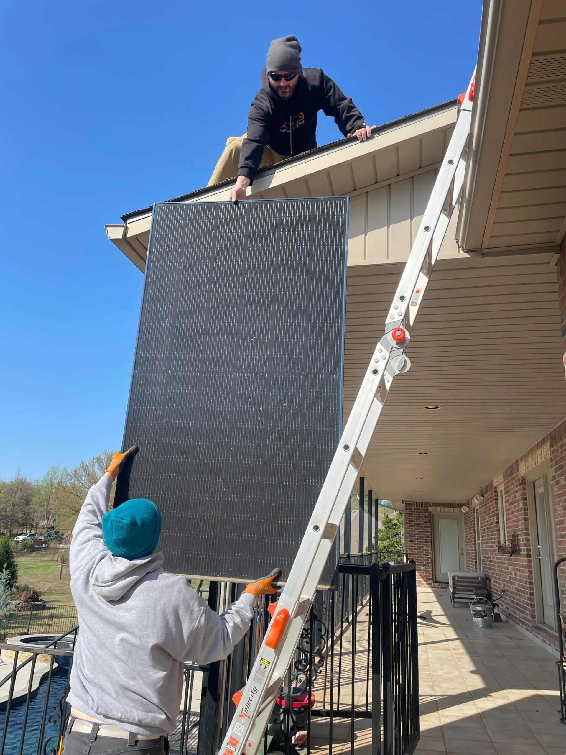 teamwork. team members transfer solar panels from the ground to the roof